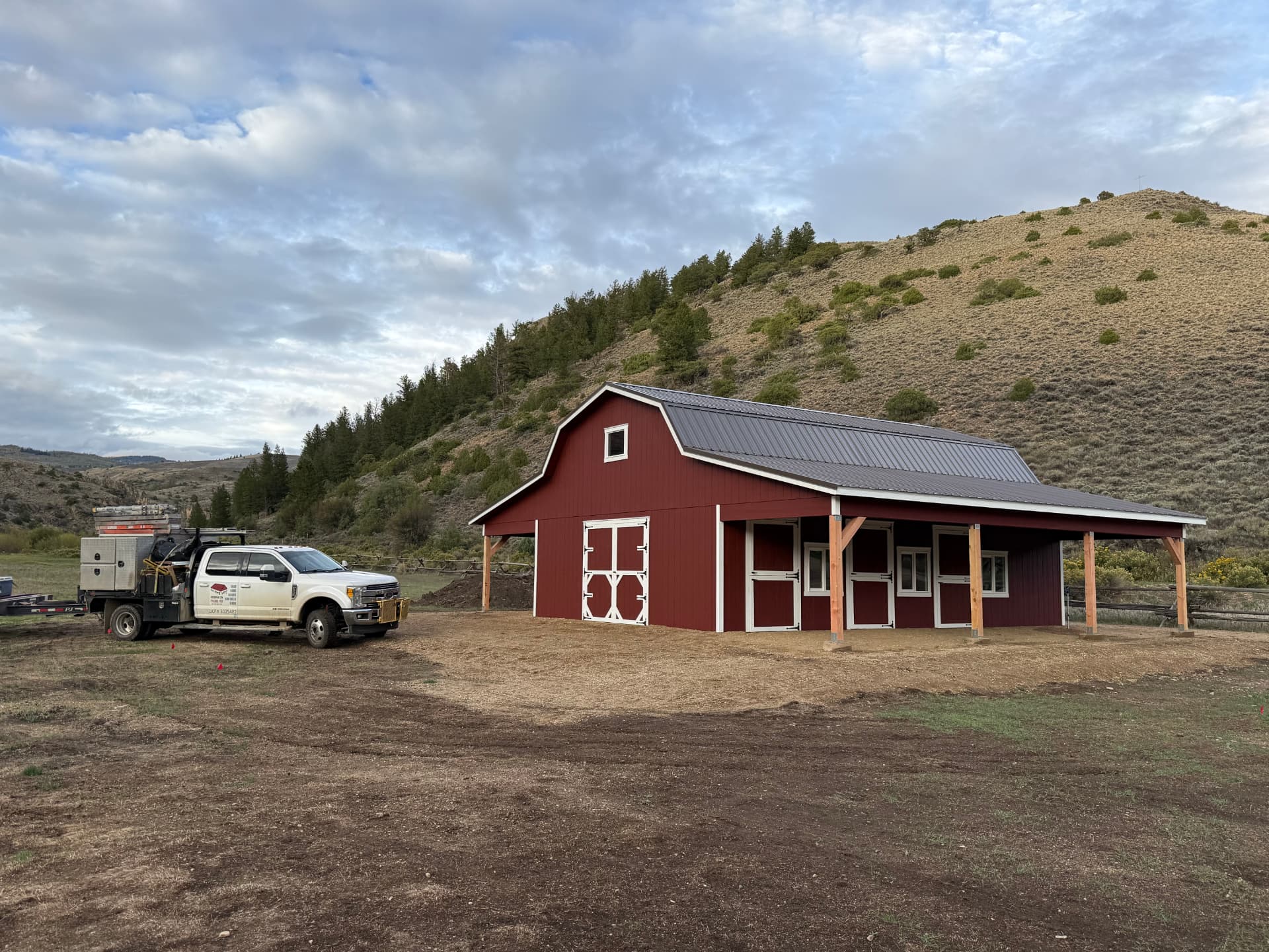 Completed metal roof on a red custom Hi Wall Barn in Parshall, Colorado with service truck nearby