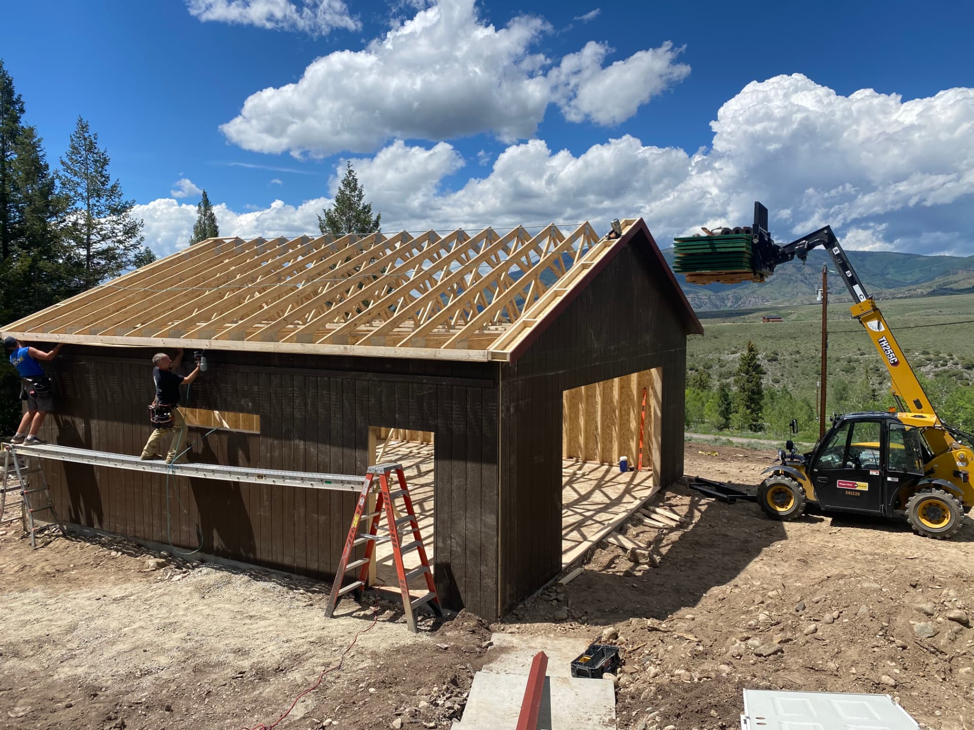 Detached garage under construction in the Colorado mountains with engineered roof trusses being set