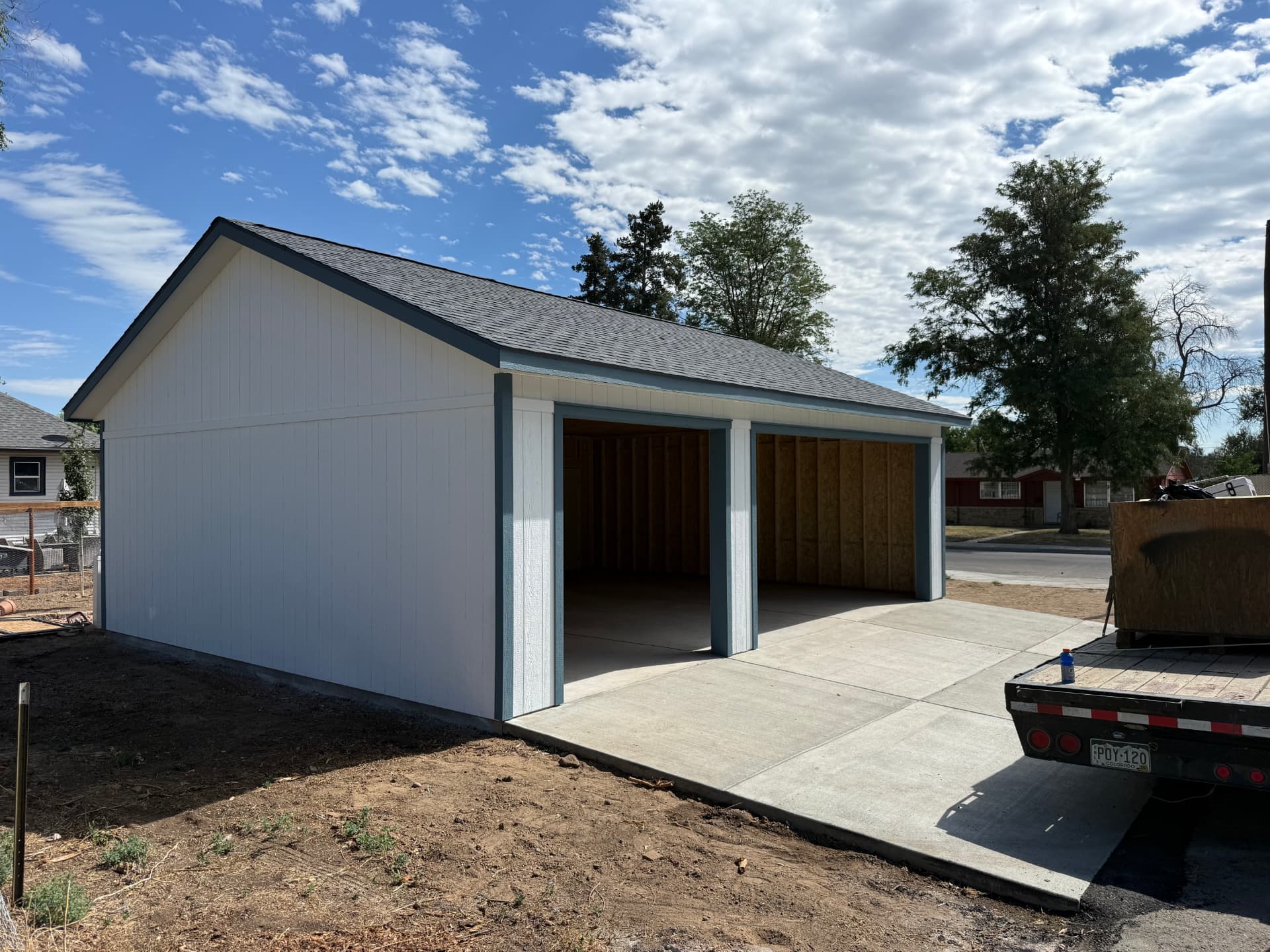 White 24×30 detached garage in Greeley with dark blue trim, open garage-door bays and new concrete driveway