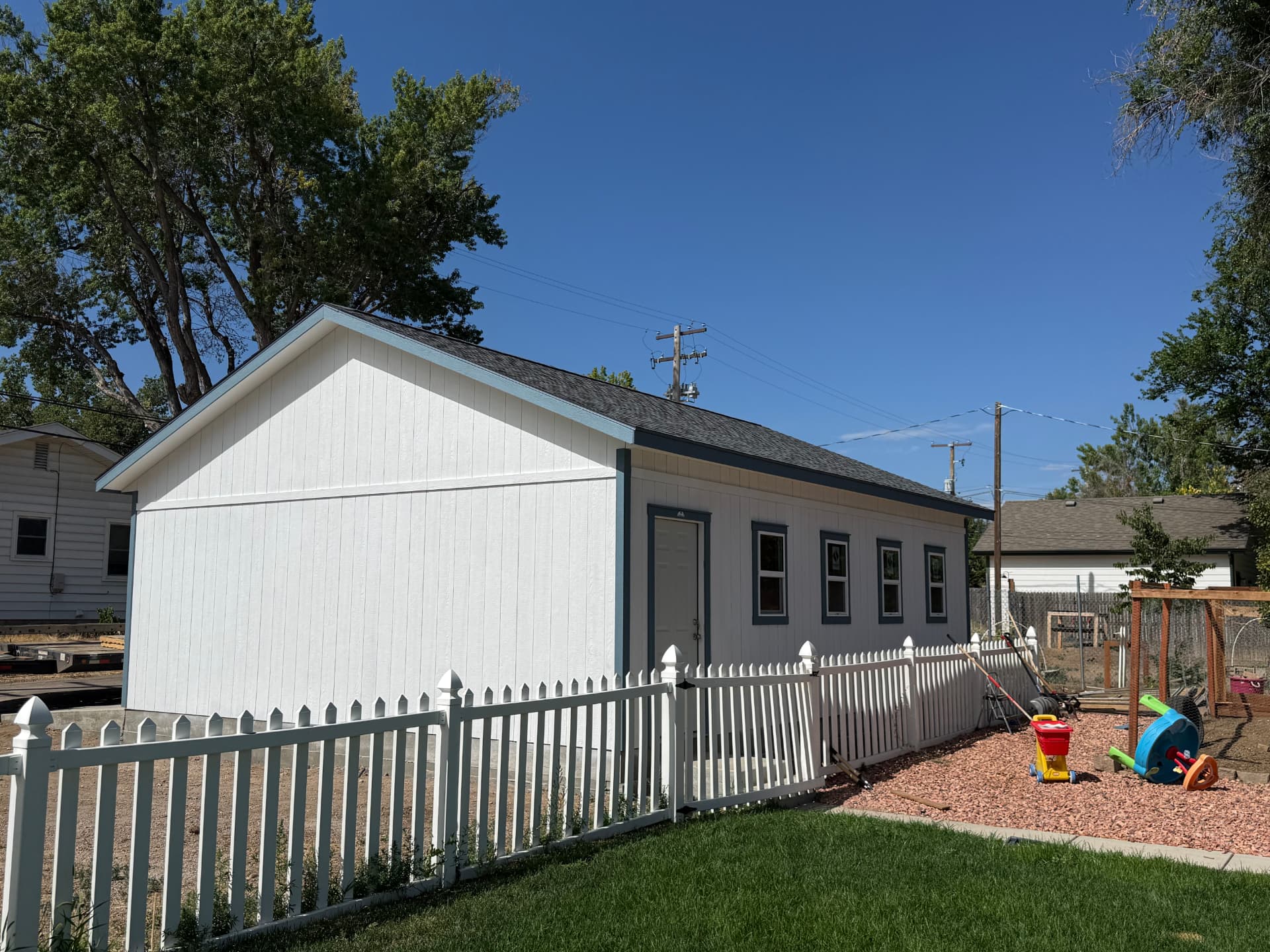 Rear side of white Greeley garage showing dark blue trim, four visible windows and a pedestrian door