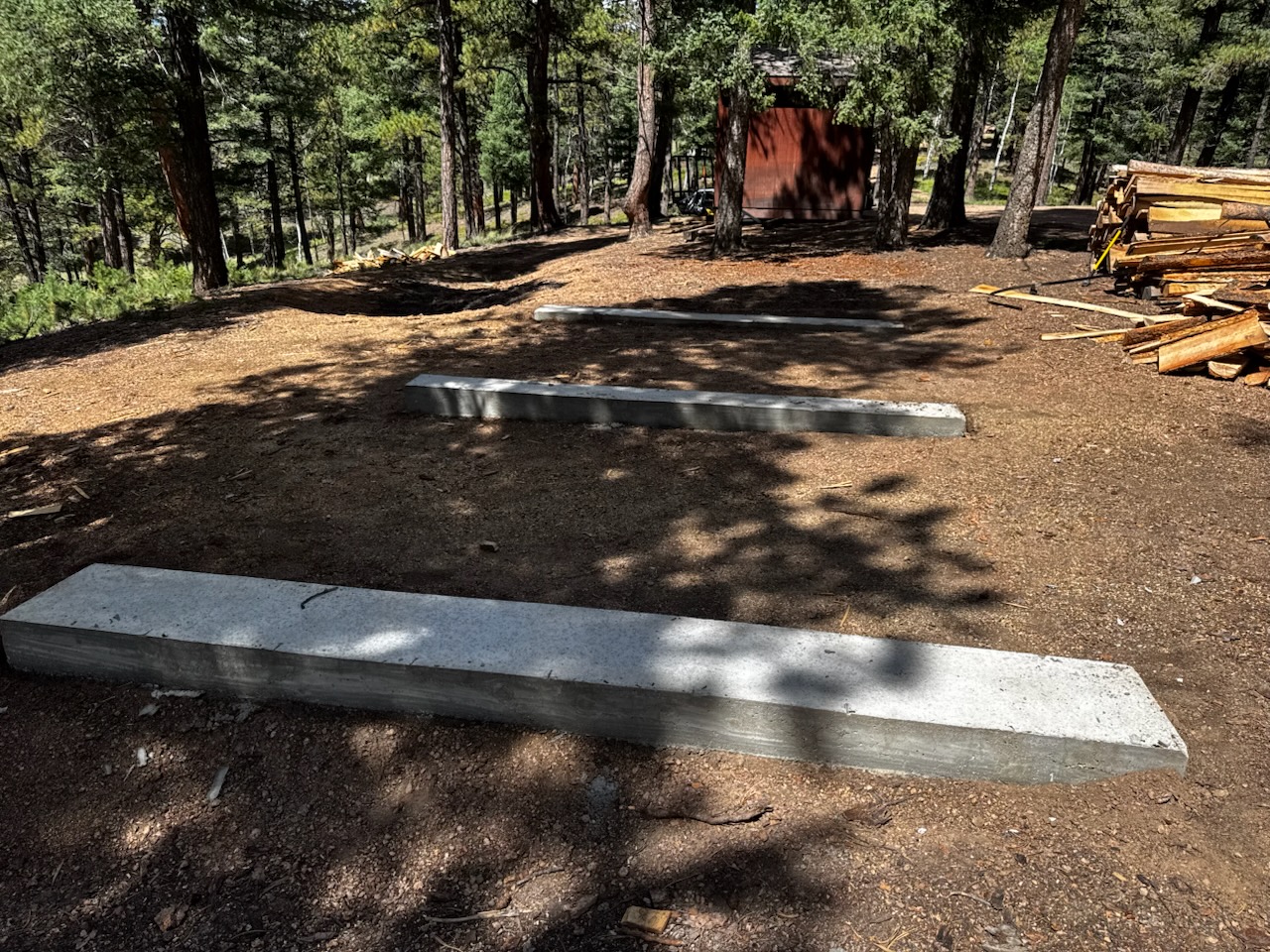 Three concrete piers set on a steep, wooded lot in Woodland Park, Colorado, ready for a 10x20 barn