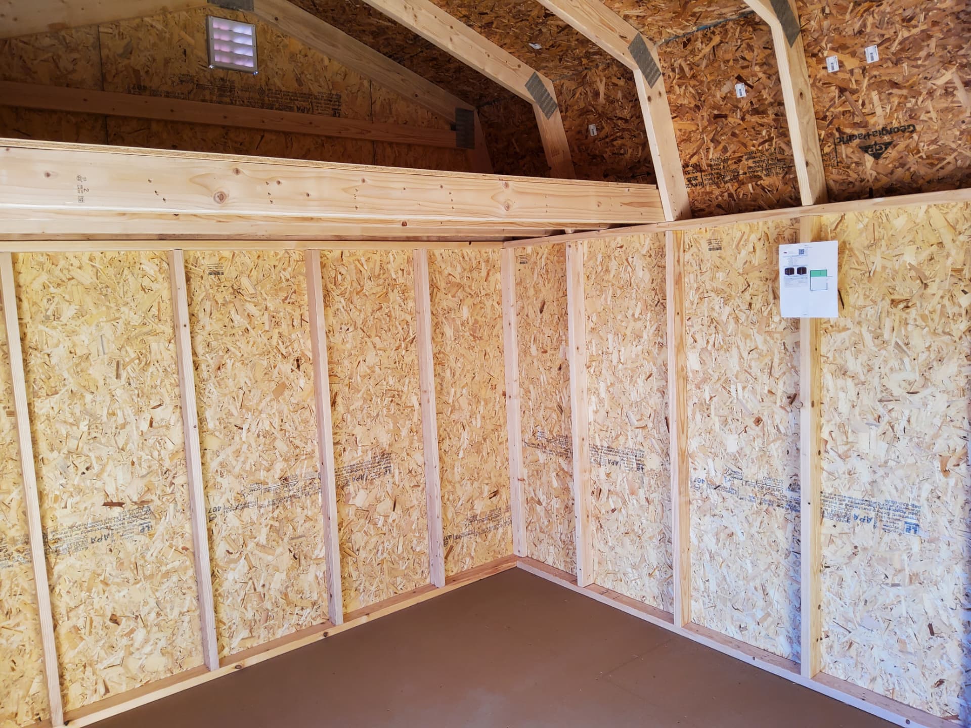 Gym shed interior shell in Colorado showing 16-inch on-center framing and electrical box before insulation and drywall
