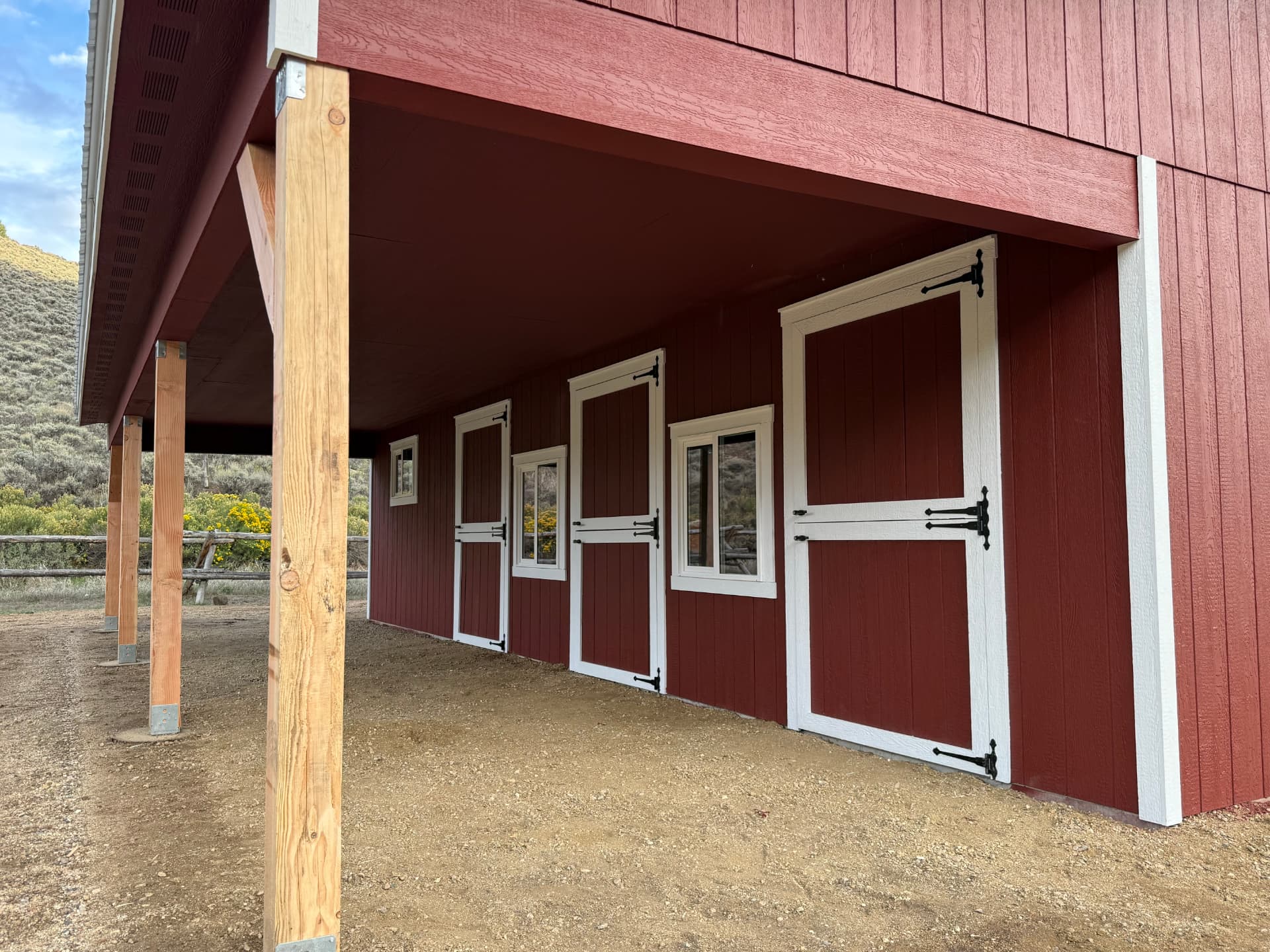 Close view of a 10-foot eave overhang with posts, doors and windows on a red custom barn