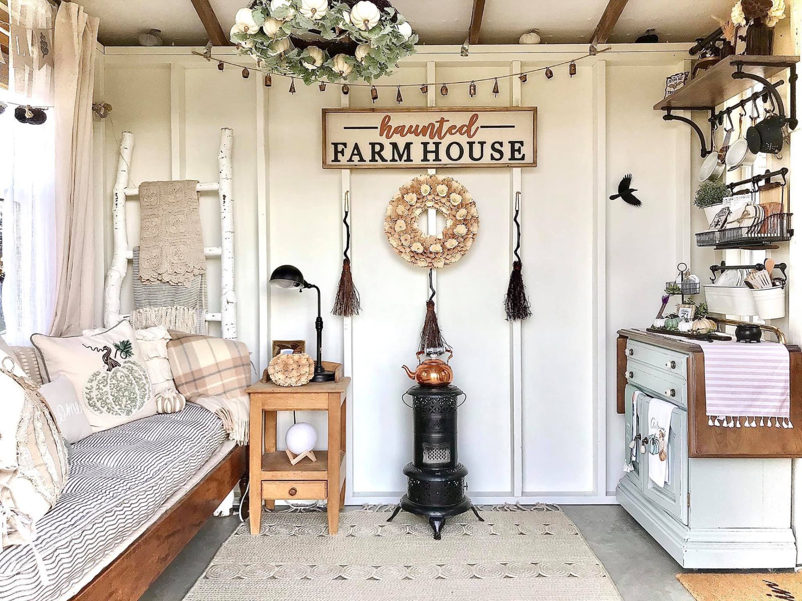 Finished interior of an Aurora 8x10 She Shed with a daybed, styled furniture, shelves and seasonal farmhouse décor