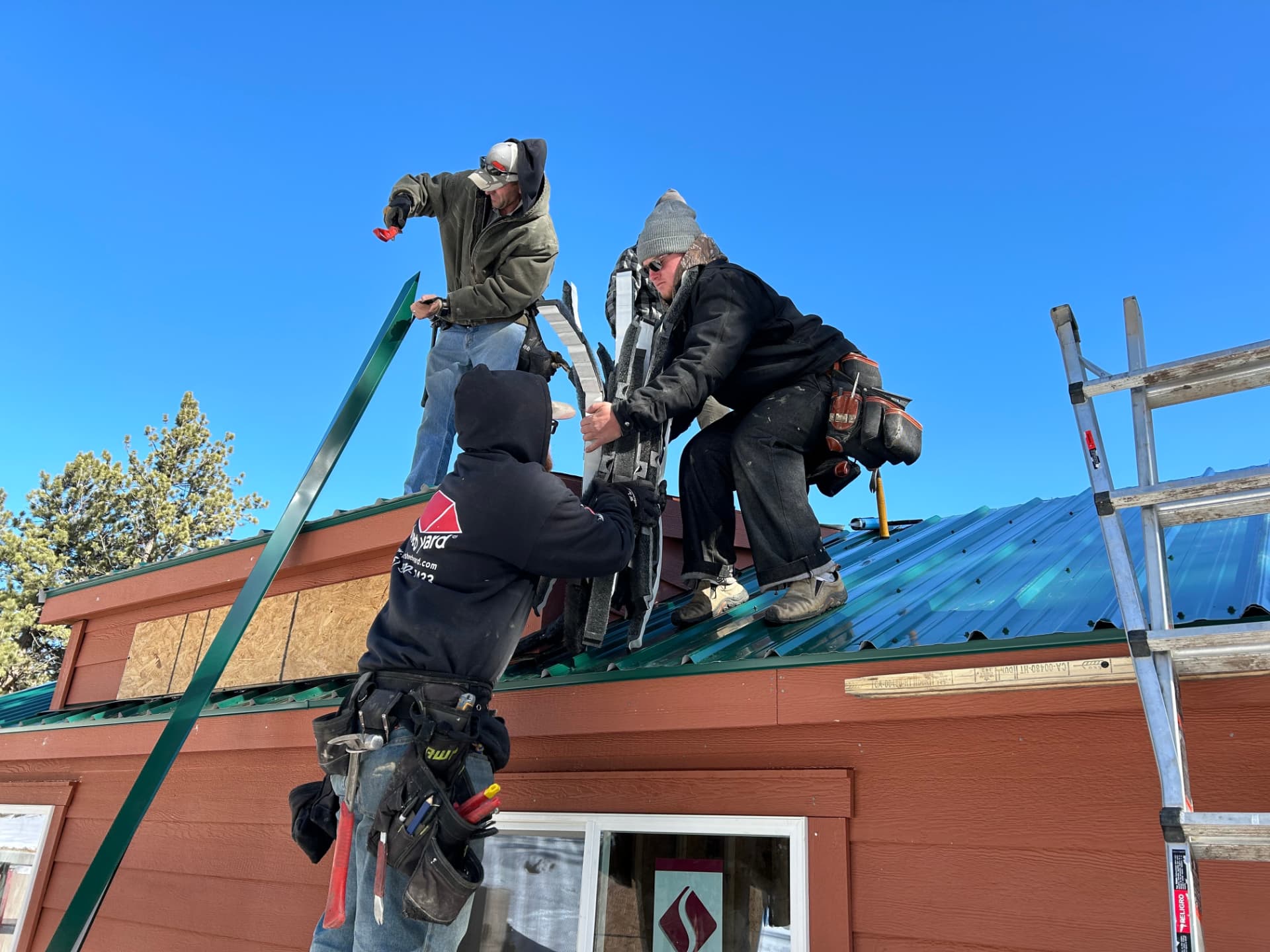 The Shed Yard crew installing a green metal roof on a site-built one-car garage