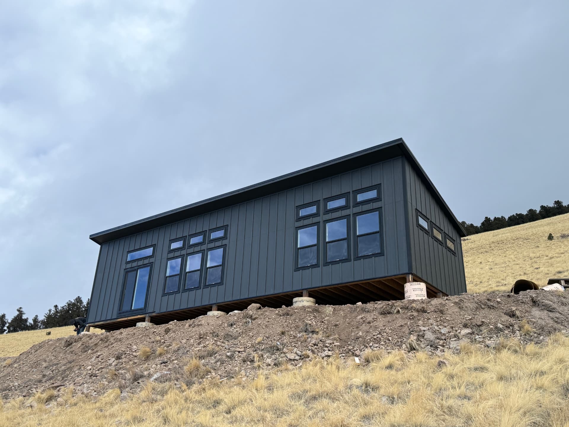 Dark modern shed-roof home shell on a Colorado hillside with panoramic windows