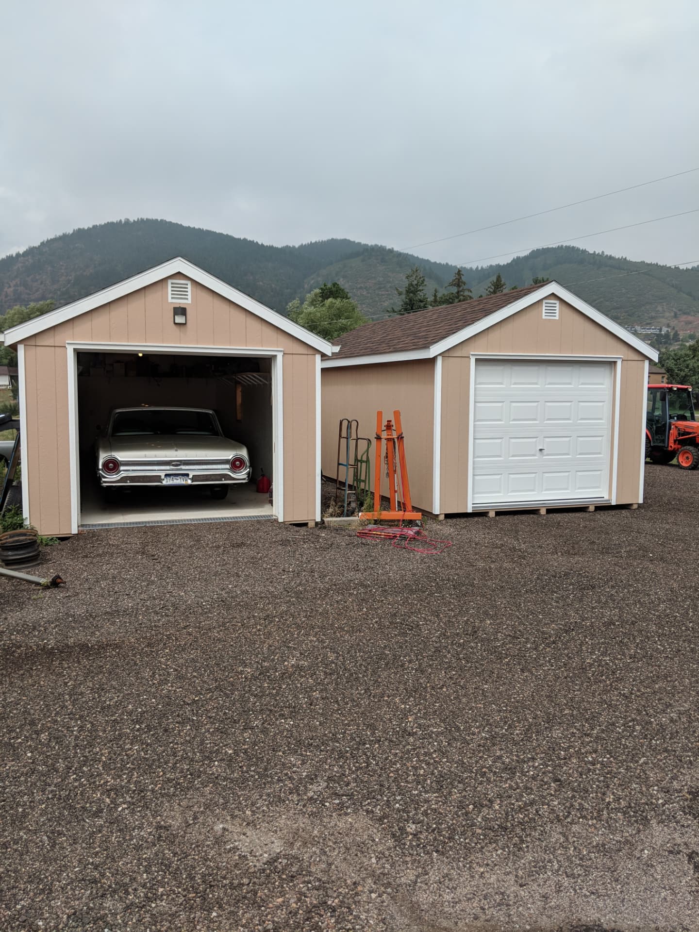 Classic car parked inside a one-car garage beside a second garage building in Colorado