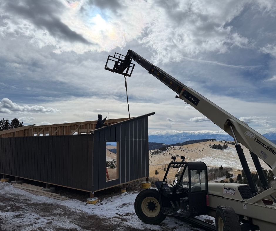 Shed walls framed on concrete piers at a snowy high-elevation Colorado site, ready for snow-load roof trusses
