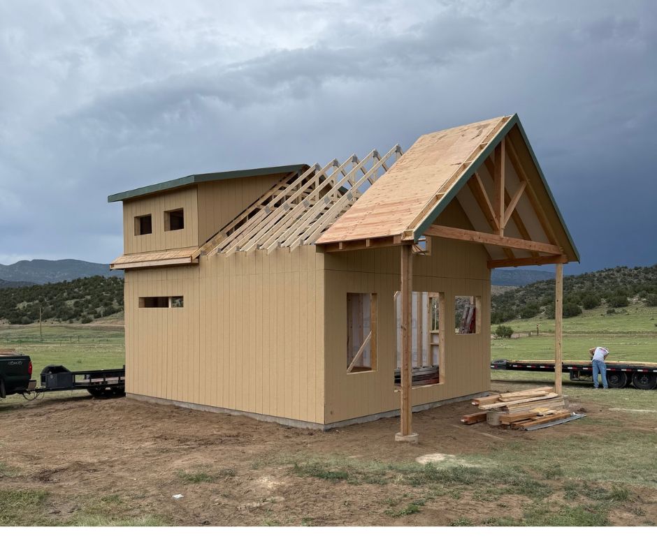 Engineered roof trusses rated for Colorado snow loads being installed on a two-story shed with a covered porch