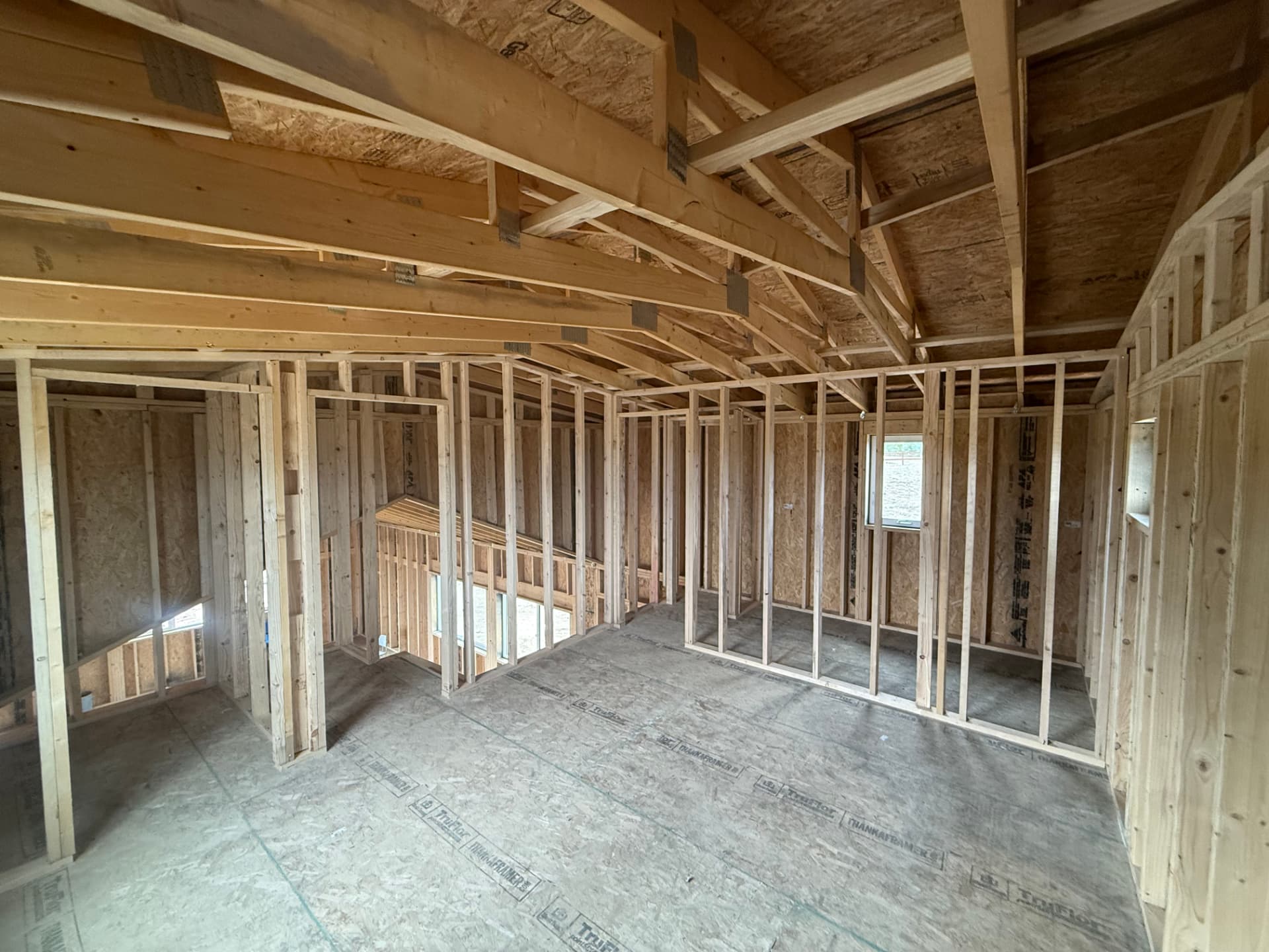 20x10 bonus loft interior framing in a Colorado home shell with open rafters, knee walls and a gable window