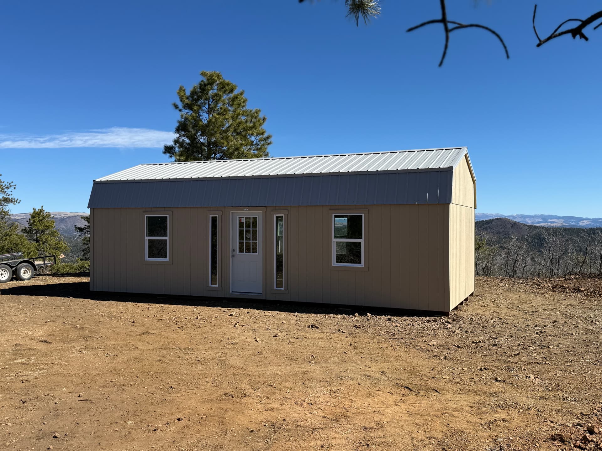 Completed tan 14x32 Hi Wall Barn with metal roof, entry door and windows on a hilltop near Canon City, Colorado