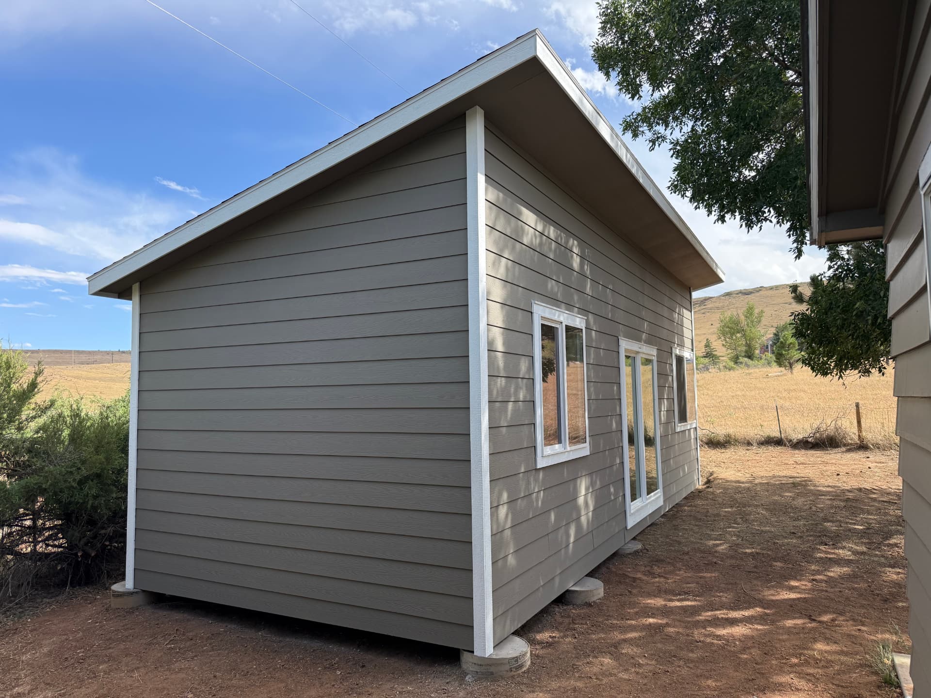Side view of a Studio Shed in Boulder, Colorado on concrete piers with foothills in the background