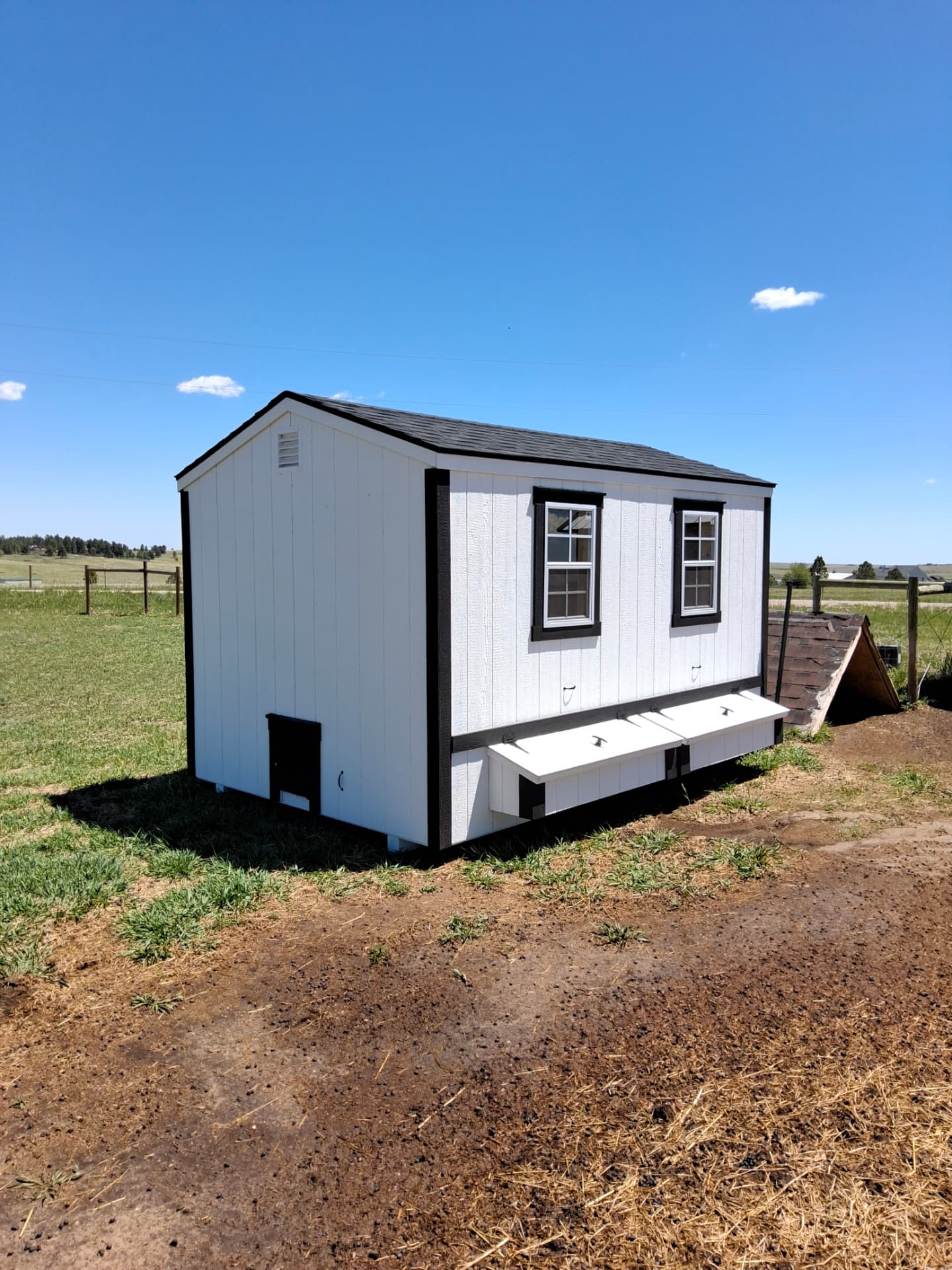 White custom chicken coop with exterior nesting boxes delivered to a Colorado property