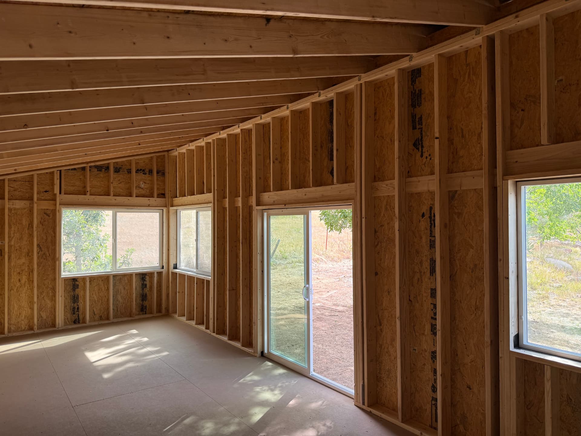 Interior framing of a Studio Shed backyard office in Boulder, Colorado with sloped ceiling and sliding glass door