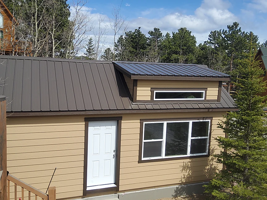 Tan Cabin shell with dark metal roof in the trees