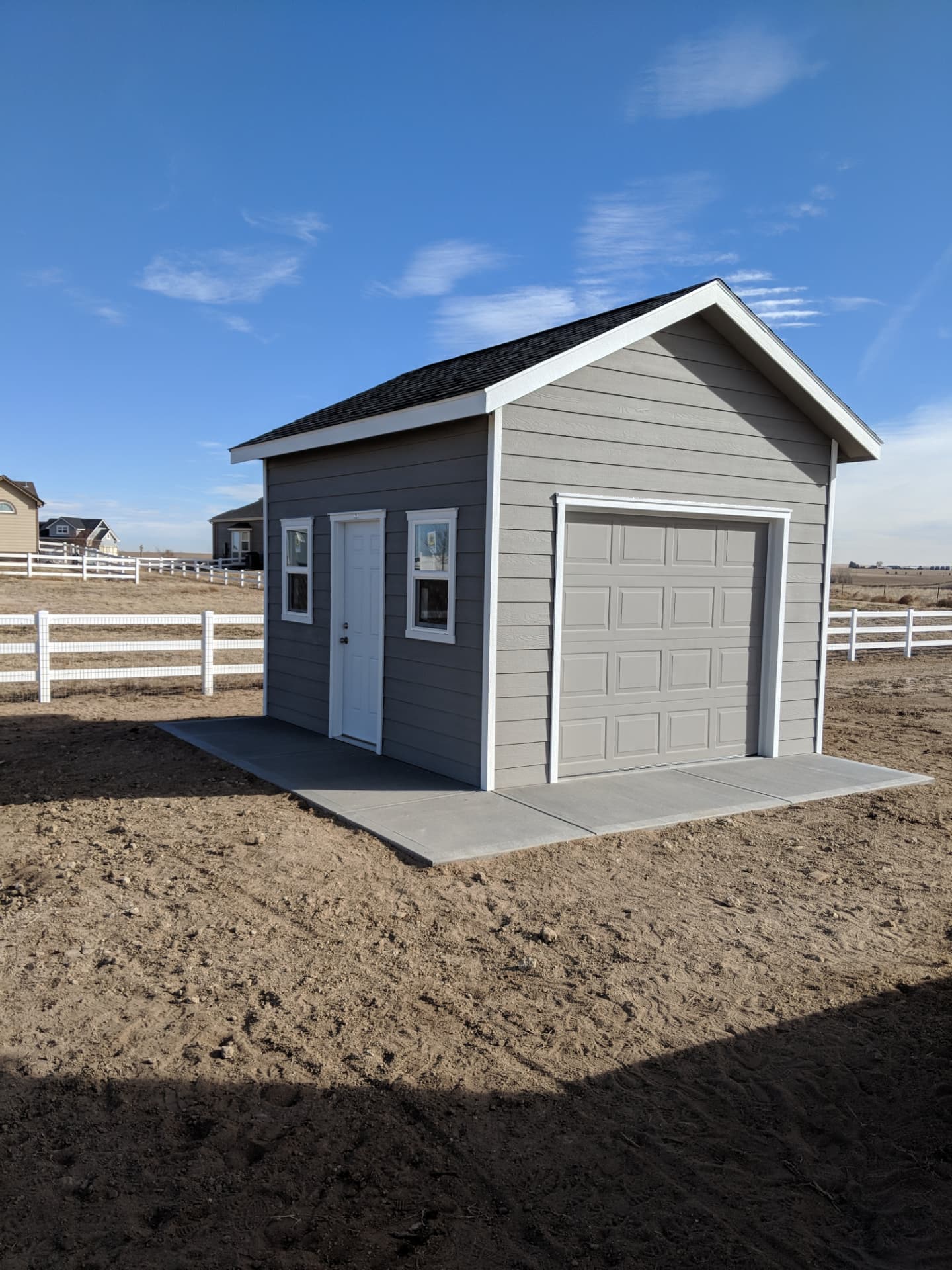 Gray detached 1-car garage with overhead door on a Colorado property